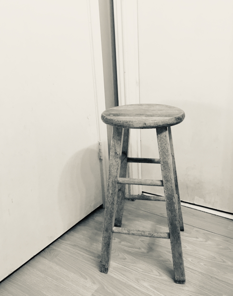 An empty stool in a corner
